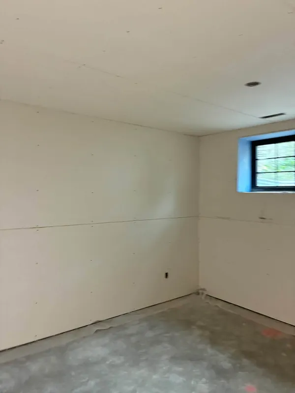 New drywall boarded throughout a Lethbridge basement, ceiling sheets hung and fasteners set