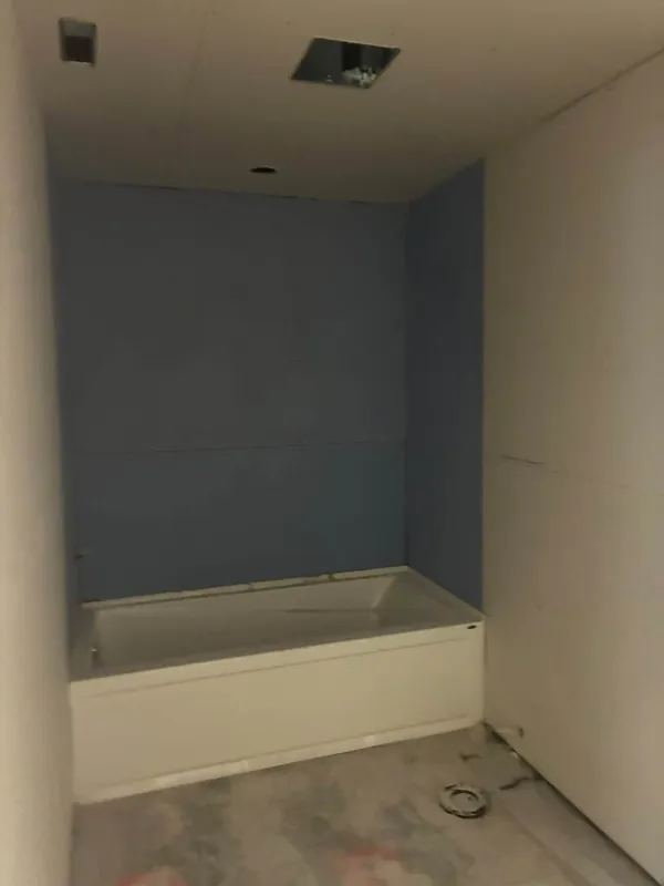 A bathtub surround boarded in moisture-resistant drywall, with the surrounding walls and ceiling hung
